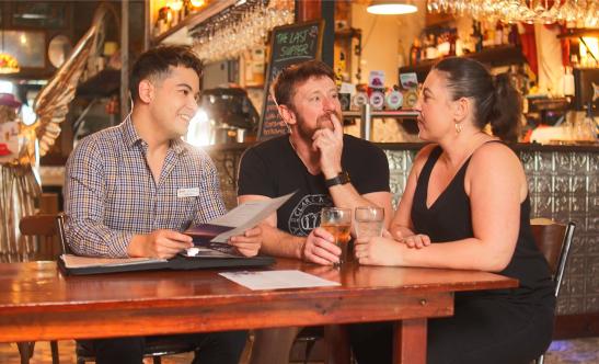 Three people talking at a bar