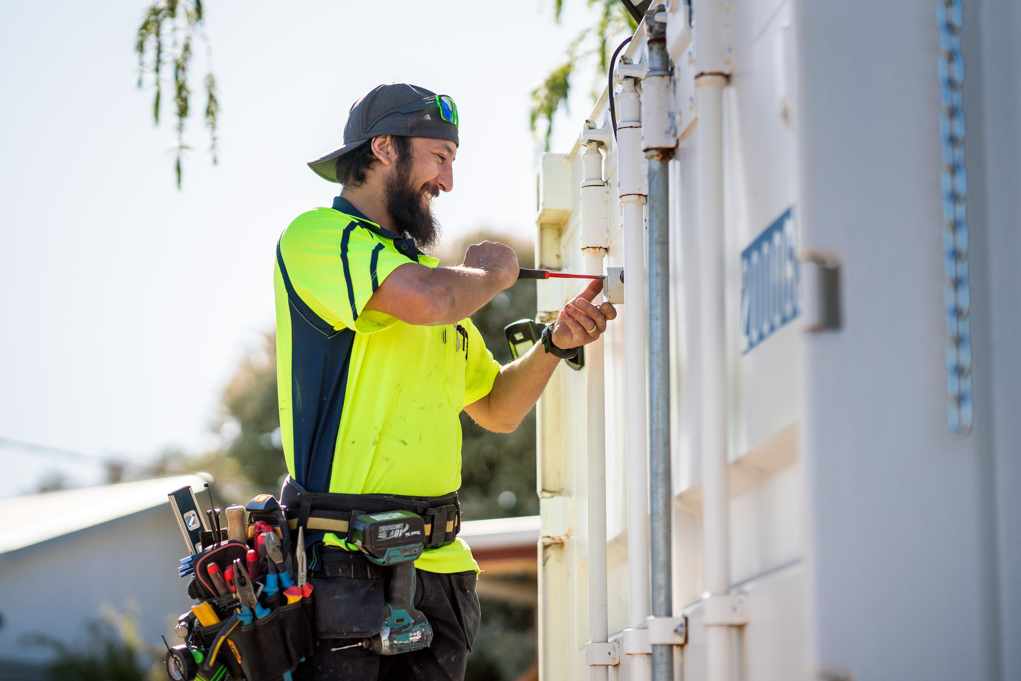 Worker using a screwdriver on a container